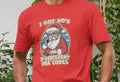 Person wearing a red T-shirt with a Santa graphic and text reading "I got ho's in different area codes," set against a backdrop of green plants.