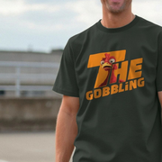 A person wearing a dark funny Christmas t-shirt with a cartoon Turkey and bold text