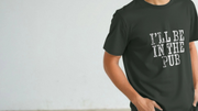 A person wearing a black funny slogan T-shirt with the playful text,