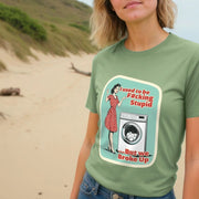 A Woman wears a green Retro T-shirt with a retro-style graphic of a woman in a red dress beside a washing machine. Text reads,