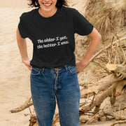 Smiling Woman on a beach in jeans and a black Retirement T-shirt with the text