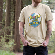 A bearded man stands in a forest wearing an Oat Birthday t-shirt with 