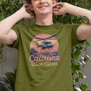 A smiling man wearing an olive green movie T-shirt featuring a helicopter and text reading 