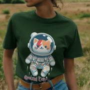 A Woman wearing a green Music T-shirt featuring a cute cat in a spacesuit with a red lightning bolt on its face, resembling an astronaut, against a blurred nature backdrop.