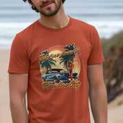Man on beach wearing an orange music T-shirt with a vintage car, palm trees, and a woman in a sunset scene, text: 
