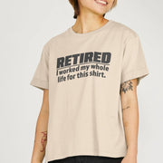 A Woman smiles, wearing a beige Retirement T-shirt with the text 