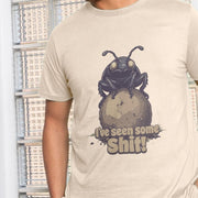 A man wearing a beige, funny animal graphic shirt with a cartoon dung beetle pushing a ball of dung. Text below reads 