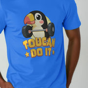 A man wears a blue novelty T-shirt featuring a cute toucan lifting weights. The words 