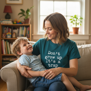 Woman and child sitting on a couch with the woman wearing a shirt that says 'Don't grow up It's a trap'.