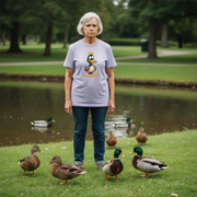 Woman standing in a park with ducks around her, wearing a t-shirt with a cartoon duck